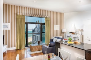 A modern living room with a glass door leading to a balcony overlooking a beach.