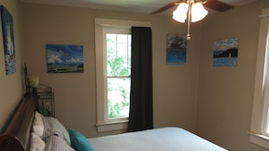 A bedroom with a bed, a window, and artwork on the walls. - Historic Seneca Bungalow (Seneca)