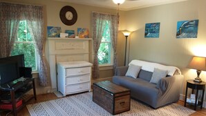 A living room with a sofa, a coffee table, a TV stand, a dresser, and a patterned rug. - Historic Seneca Bungalow (Seneca)
