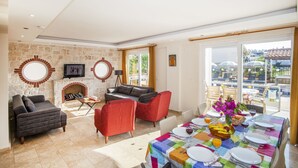 A spacious living area with a fireplace, comfortable seating, and a dining table set for a meal. - 4 Ensuite Bedrooms Private Heated Outdoor Pool (Mugla)