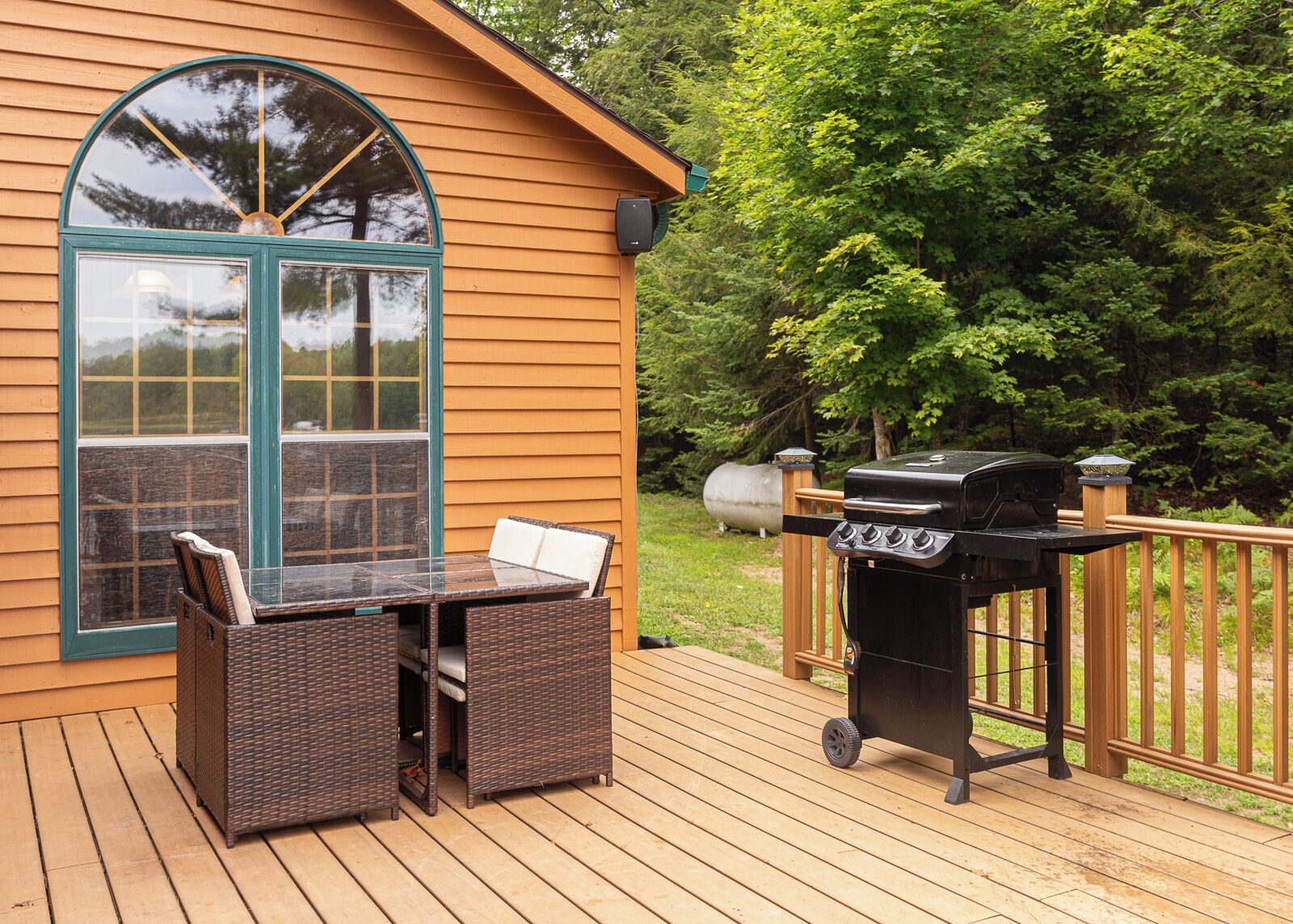 Una terrazza con tavolo e sedie, un barbecue e un'ampia finestra.