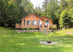 Une cabane en bois dotée d’une terrasse, entourée d’une forêt.