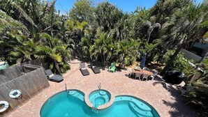 A pool area with a central pool, surrounding lounge chairs, and a wooden table with chairs.