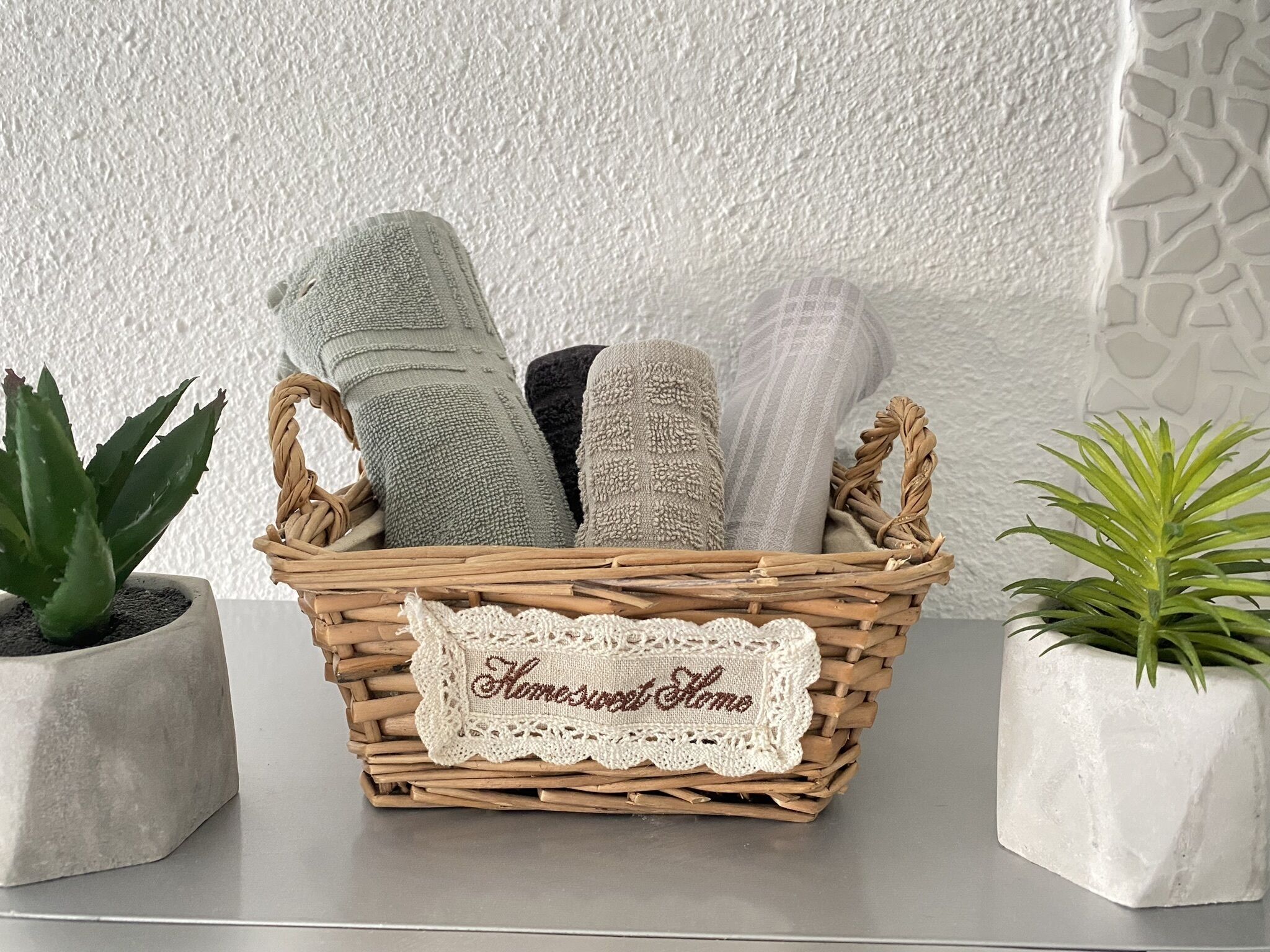 Una cesta de mimbre con toallas y una etiqueta que dice 'Home Sweet Home'.