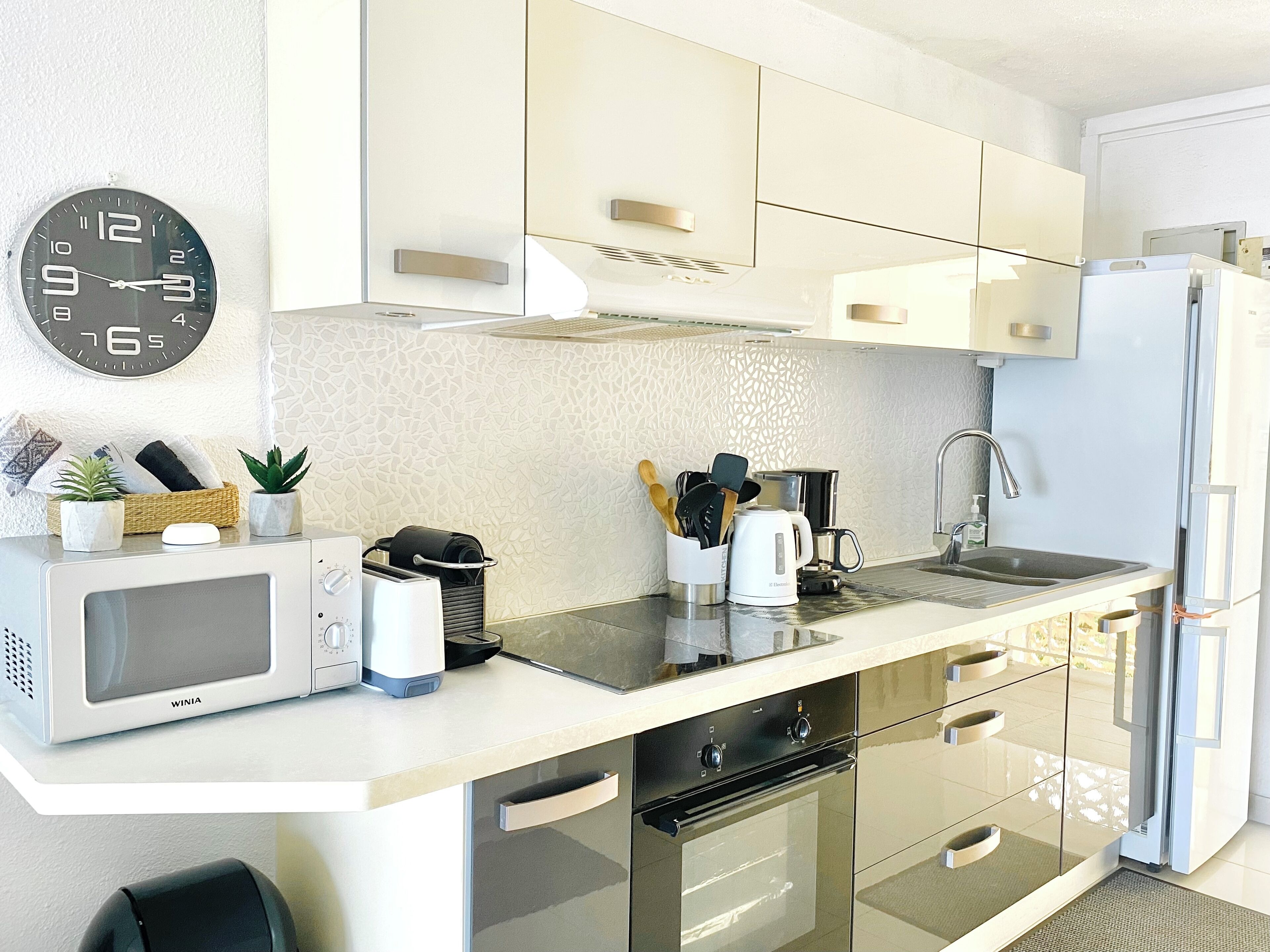 A modern kitchen with a microwave, toaster, kettle, and a sink.