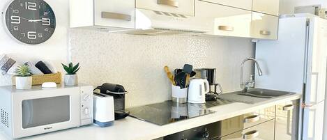 A modern kitchen with a microwave, toaster, kettle, and a sink.