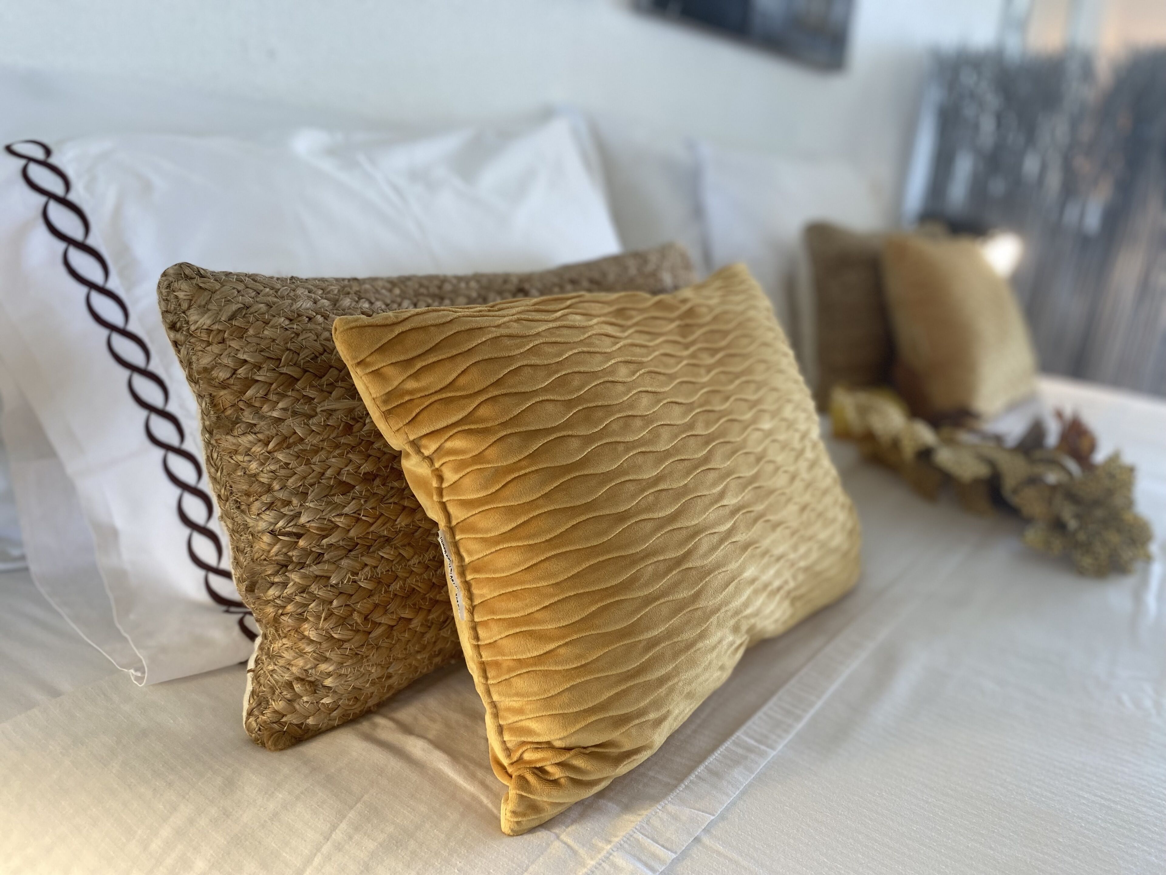 Una cama con dos almohadas acolchadas y una blanca con diseño de cadena.