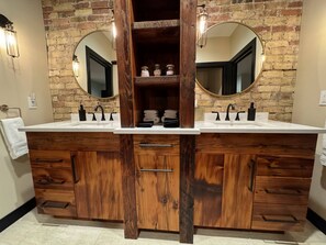 A bathroom with a double vanity, wooden cabinets, and two large mirrors.