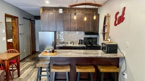 A modern kitchen with a marble island, bar stools, and a hanging light fixture. - Apex Mountain ~ Precision Palace ~ Apex Mountain Inn (Apex Mountain Resort)