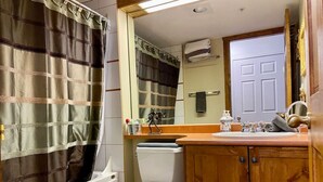 Un baño con cortina de ducha, inodoro, lavabo y armarios de madera.