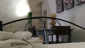 Une chambre d’hôtel avec un lit, un bureau et une chaise. Il y a des serviettes sur le lit et une plante sur le bureau.