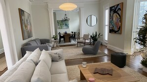 A spacious living room with a large sectional sofa, a wooden coffee table, and a dining area in the background.