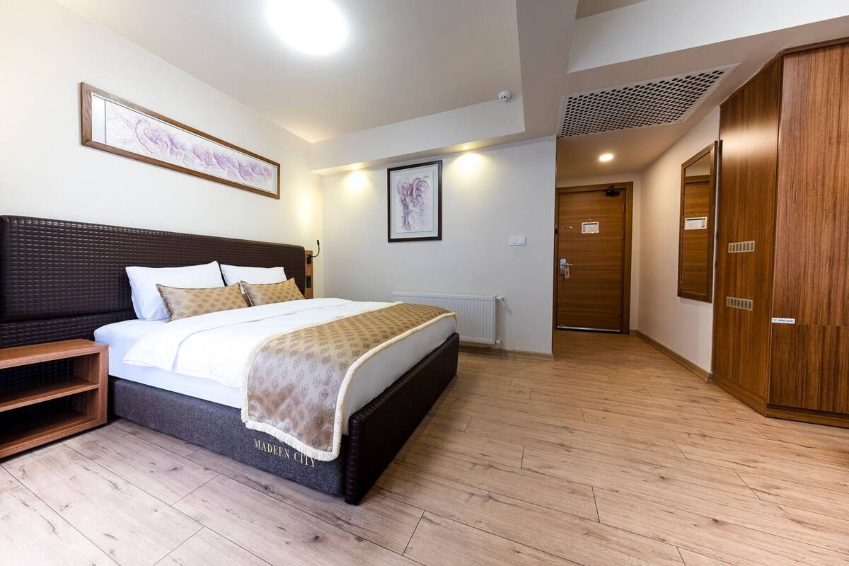 Een moderne hotelkamer met een groot bed, een houten garderobe en een lijstwerk met kunst aan de muur.