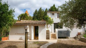 Una casa de dos pisos con tejado de tejas, un pequeño jardín y un sendero de piedra que lleva a la entrada.