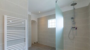 Un baño moderno con cabina de ducha de vidrio, calefacción integrada y ventana que proporciona luz natural.