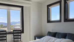A bedroom with a bed, a desk, two chairs, a window, and a ceiling fan. - Ice Skating Suite 202 at Granby Dairy Suites (Granby)
