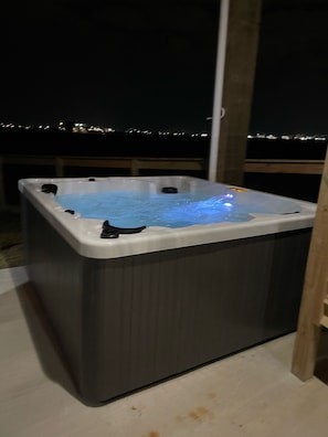 Ein Whirlpool mit blauer Beleuchtung, auf einem Balkon mit Blick auf die Stadtlichter.