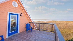 Eine Holzterrasse mit einem blauen Stuhl und einer Tür mit Glasfenster.