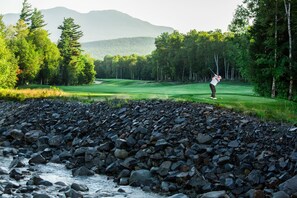 A golf course with a rocky foreground and a river.