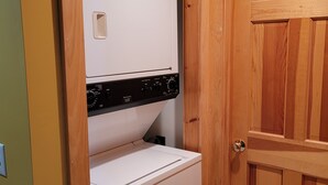Lavadora y secadora compactas instaladas dentro de un armario de madera con puerta.