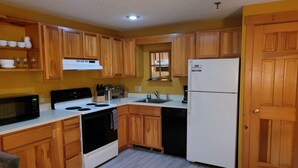 Una cocina con armarios de madera, un refrigerador blanco, un microondas, una estufa y un lavamanos.