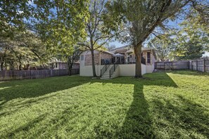 A residential property with a well-maintained lawn, a wooden fence, and a two-story house with a visible staircase leading to the entrance.