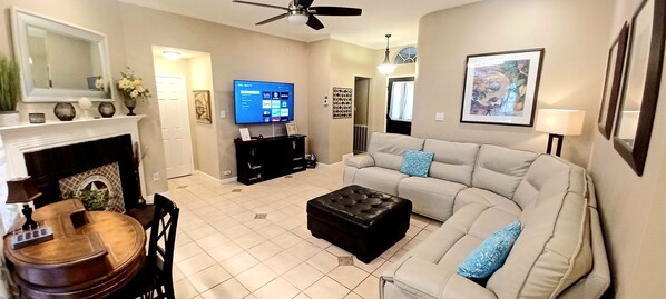 Una sala de estar con chimenea, televisor, sofá y mesa de centro.