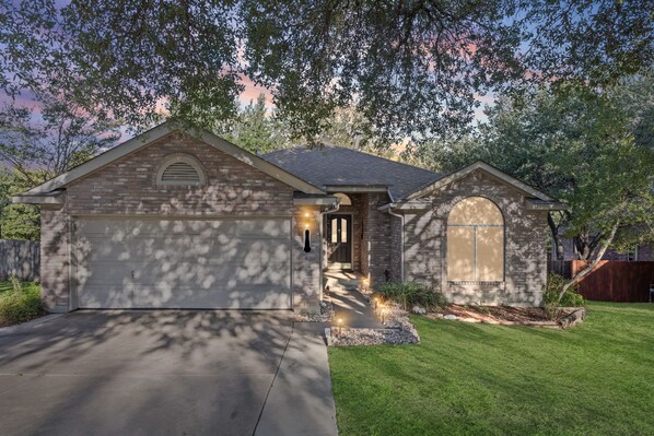 A residential house with a garage, a front entrance, and a well-maintained lawn.