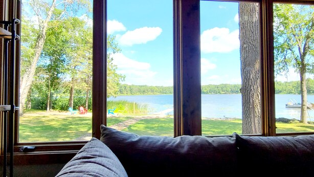 A room with large windows offering a view of a lake and greenery. - Private Beach, Beautiful Lake Home, Fishing, Recreation - Everything You Need! (Crosslake)
