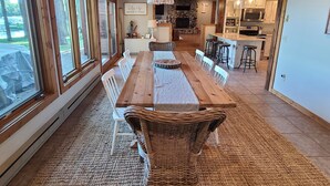 A spacious dining area with a long wooden table, wicker chairs, and a chandelier. - Private Beach, Beautiful Lake Home, Fishing, Recreation - Everything You Need! (Crosslake)