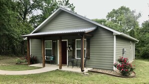 A single-story house with a covered porch, a front door, and a small patio area.