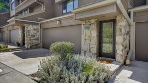 A modern multi-story residential building with stone accents and a well-maintained front yard.