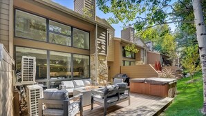 A modern outdoor deck with a fire pit, seating area, and hot tub.