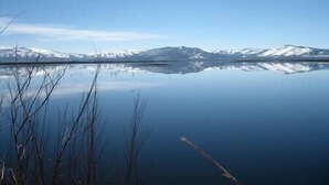 Un lac paisible, avec des montagnes en arrière-plan.