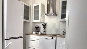 A compact kitchen with white cabinetry, a coffee machine, and a dishwasher. - Charming apartment sea view (HYERES)