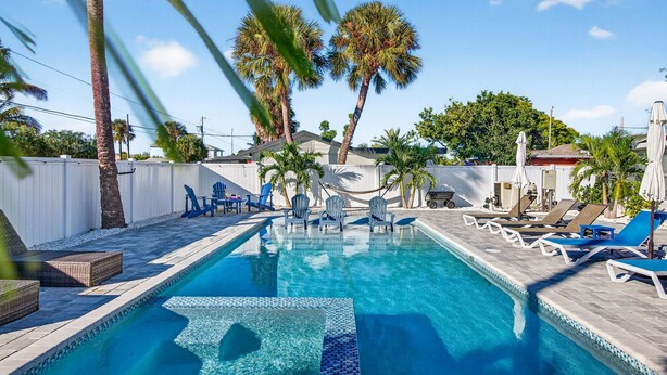 Una piscina con sillas de descanso y palmeras.