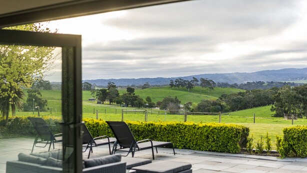 A patio with outdoor furniture overlooking a green landscape.