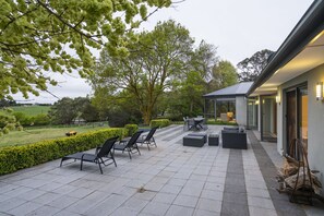 An outdoor patio with seating, a fire feature, and a view of the surrounding landscape. - Farm Stay at The Farm Barn (Hahndorf)
