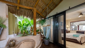 Quarto com cama, cadeira suspensa e planta em vaso.