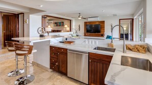 Uma cozinha moderna com bancada de mármore, armários de madeira e máquina de lavar louça embutida.
