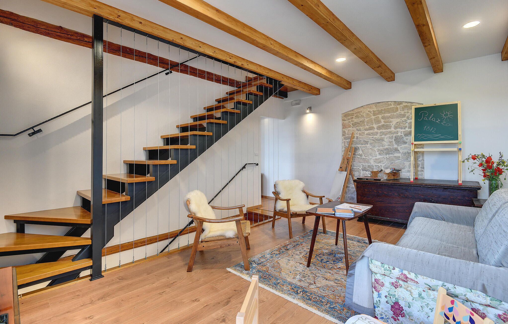 A modern interior with a wooden staircase, a stone wall, and a chalkboard.