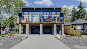 Une maison à deux étages avec un garage, un balcon et une vue sur les montagnes.