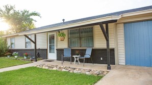 Een gelijkvloers huis met een overdekte veranda, een klein terras en een voordeur.