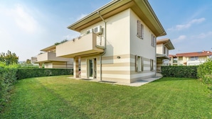 Ein modernes, zweistöckiges Haus mit Flachdach, Balkon und gepflegtem Rasen.