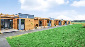 A row of modern, wooden cabins with sliding glass doors, a covered patio, and a well-maintained lawn. - Stunning home in Nowecin with kitchen (Nowecin)