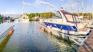 A marina with several boats docked, a wooden pier, and a building with a red roof in the background. - Stunning home in Nowecin with kitchen (Nowecin)