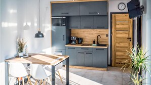 A modern kitchen with grey cabinets, a wooden countertop, a coffee machine, and a sink. There is a dining table with chairs and a pendant light. - Stunning home in Nowecin with kitchen (Nowecin)
