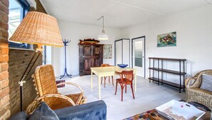 Un salon chaleureux avec des meubles en osier, une table à manger et un tapis aux couleurs vives.
