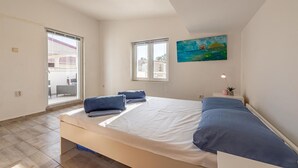 A bedroom with a bed, two windows, a painting, a bedside lamp, and a view of the outside. - 1 bedroom beautiful apartment in Vir (Vir)