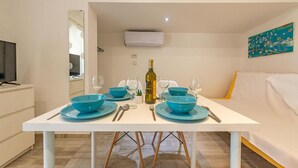 A dining area with a white table, blue bowls, wine glasses, and a bottle of wine. - 1 bedroom beautiful apartment in Vir (Vir)